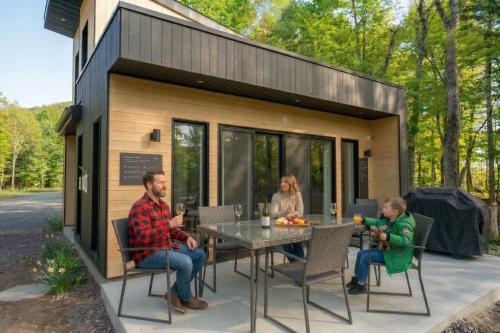Eine Familie sitzt an einem Tisch vor einem winzigen Haus in der Unterkunft Elios Private Spa & BBQ, Lake & Golf in Brownsburg