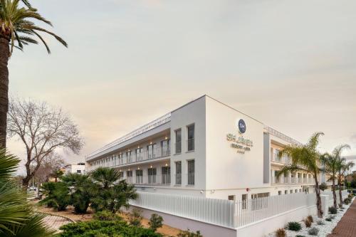 a white building with palm trees in the foreground at SH Jávea in Jávea