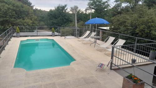 a pool with chairs and an umbrella on a patio at Cuesta Blanca cabañas in Cuesta Blanca