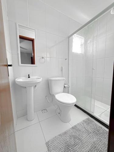 a white bathroom with a toilet and a sink at Suítes em Bacaxá Saquarema in Saquarema