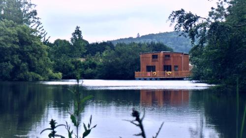 a house sitting on the side of a lake at Cabanes flottantes et gîtes au fil de l'eau in Colleville