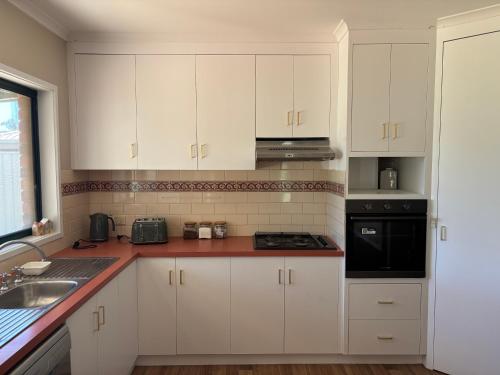 a kitchen with white cabinets and a stove top oven at Manor on McIntyre in Horsham