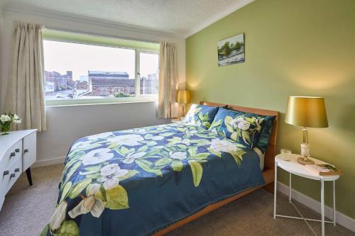 a bedroom with a bed with a blue comforter and a window at Host & Stay - Beachcomber Cottage Apartment in Morecambe