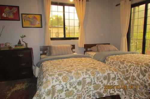 a bedroom with two beds and two windows at BIG J'S Farm House in Dhulikhel