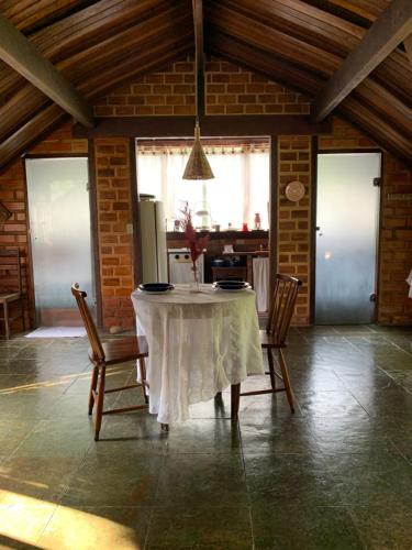 a table in a room with chairs and a kitchen at Chalé Vale do Amor in Araras Petropolis