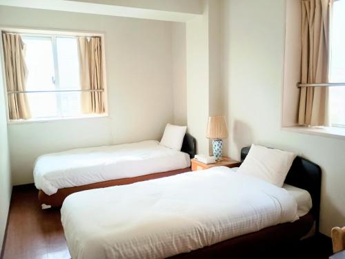two beds in a room with two windows at Hotel-澄Sumi-波の上ビーチ徒歩5分 in Naha