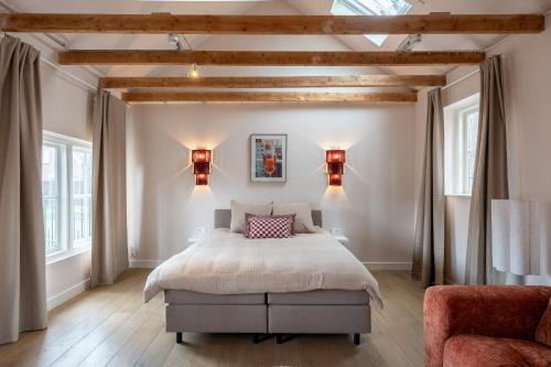 a bedroom with a bed and two windows at Luxe appartement in het hart van Castricum in Castricum