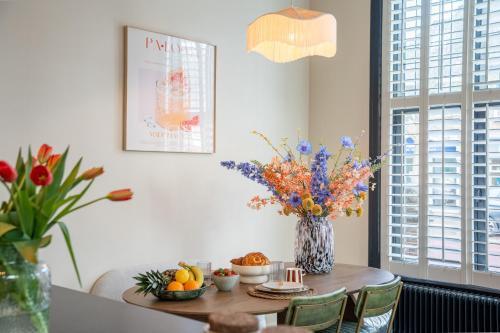 a dining room table with a vase of flowers on it at Luxe appartement in het hart van Castricum in Castricum