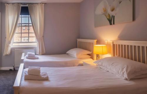two beds in a room with a window at The Three Coopers in Bedale
