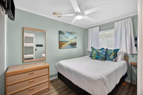 a bedroom with a bed and a dresser with a mirror at SC309A: 309A Sea Cabin in Isle of Palms