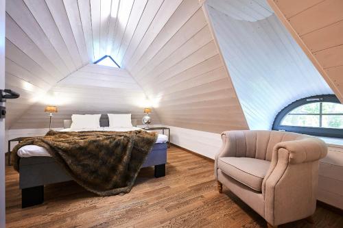 a attic bedroom with a bed and a chair at Bottengarn Boutique Guesthouse - Farm in Igaküla
