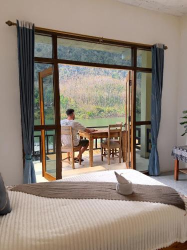 a man sitting at a table in front of a glass door at Views Backpackers Hostel in Nongkhiaw