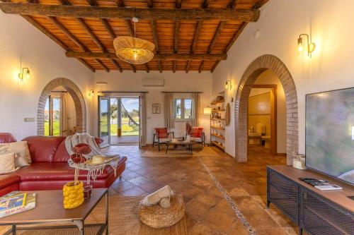 a living room with a red couch and a tv at Monte do Sossego by Portugal Active in Ferreira do Alentejo