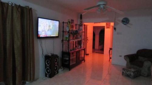 a living room with a flat screen tv on the wall at Tina's Guest House in Ocho Rios