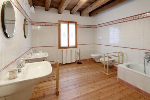 a bathroom with two sinks and a tub and two toilets at Agriturismo Marzanino in Torre di Mosto