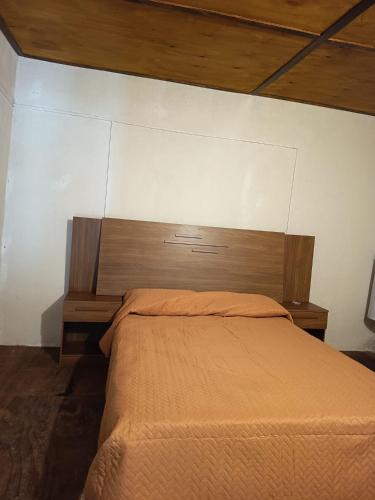 a bedroom with a bed with a wooden headboard at Cordero Atado Hotel Apart in Ocean Park