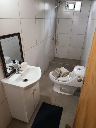 a bathroom with a sink and a toilet and a mirror at Cordero Atado Hotel Apart in Ocean Park