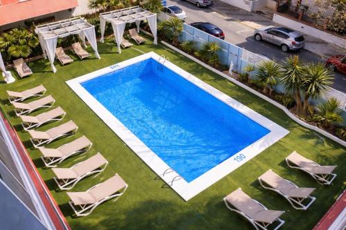an overhead view of a pool with chairs and a table at Apartamentos El Velero in Torremolinos