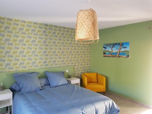 a bedroom with a blue bed and a yellow chair at les terrasses d'arutoli in Porto-Vecchio