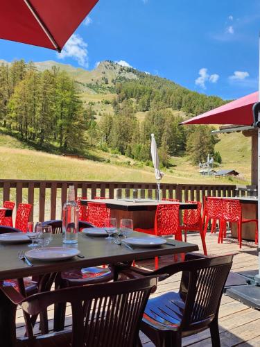 a table with chairs and an umbrella on a deck at Hôtel Chalet Sainte-Anne in Condamine-Châtelard