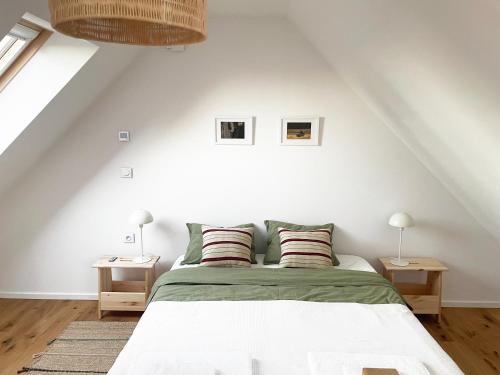 a white bedroom with a bed and two lamps at Skrzydła Biebrzy- Eco Cottage nad rzeką Narwią - Biebrza NP in Niwkowo