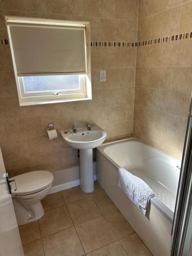 a bathroom with a toilet and a tub and a sink at Coastal Retreat at Waterside Park in Corton