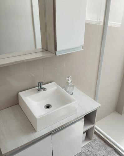 a bathroom with a white sink and a mirror at Apartamento no centro de Caxias com elevador e garagem in Caxias do Sul