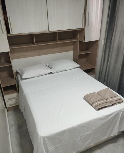 a bedroom with a bed with white sheets and cabinets at Apartamento no centro de Caxias com elevador e garagem in Caxias do Sul