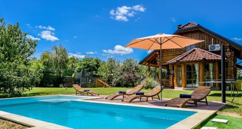 a pool with chairs and an umbrella next to a house at Kuća lješnjaka in Ludbreg