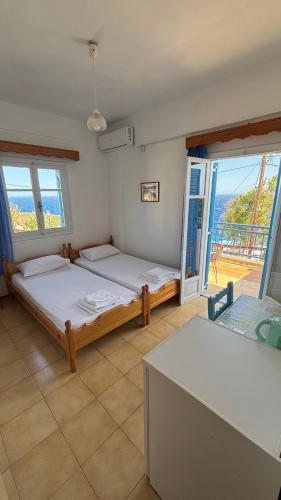a bedroom with two beds and a balcony at Faros Rooms Armenistis in Armenistis