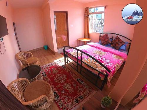 a bedroom with a bed and chairs and a window at Laskus Homestay in Darjeeling