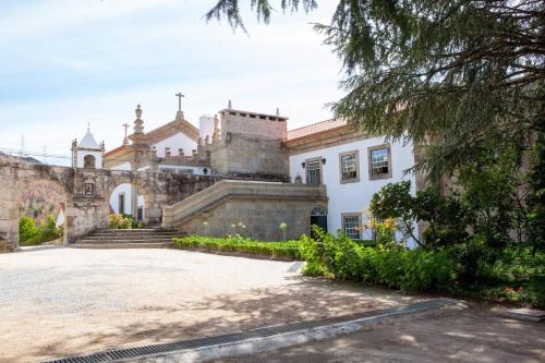 un vecchio edificio con una chiesa sullo sfondo di Casa de Quintã a Marco de Canaveses