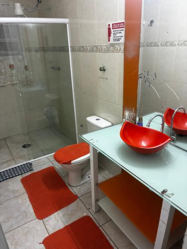 a bathroom with a red sink and a toilet at Casa 100mtrs do mar com piscina aquecida in Solemar