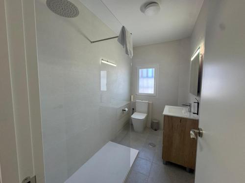 a white bathroom with a toilet and a sink at Hostal Guzman El Bueno by gaiarooms in León