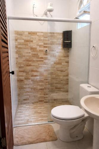 a bathroom with a shower with a toilet and a sink at Pousada Casarão Piúma in Piúma