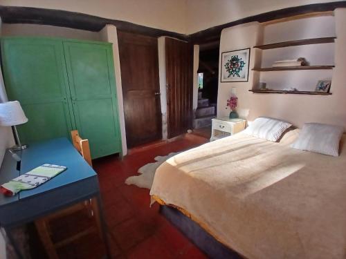 a bedroom with a large bed and a blue table at The Witch's Cottage in Urubamba