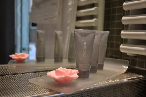 a counter with four plastic cups and pink roses at Le César Hôtel in Provins