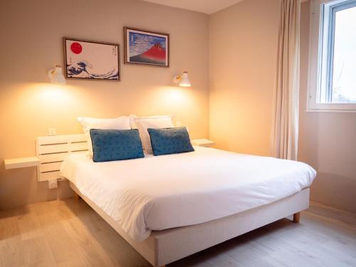 a bedroom with a large white bed with blue pillows at Fuzei Hôtel Lorient-Lanester in Lanester