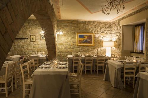 a restaurant with white tables and chairs and a stone wall at Il Melograno Agriturismo & SPA in Pianello