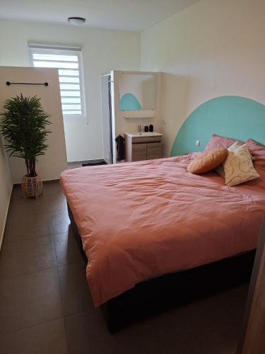 a bedroom with a large bed with orange sheets and a plant at CocoCasa 22 Stylish Luxury Apartment with Pool near Jan Thiel Beach in Willemstad