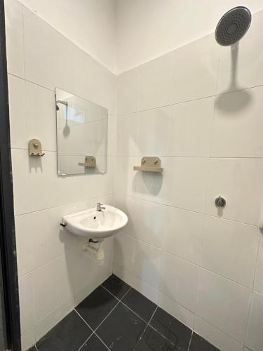 a white bathroom with a sink and a mirror at Eryna Homestay in Nibung Tebal