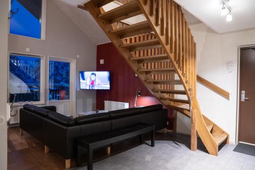 a living room with a black couch and a wooden staircase at Hovfjällstoppens Stugby in Överbyn