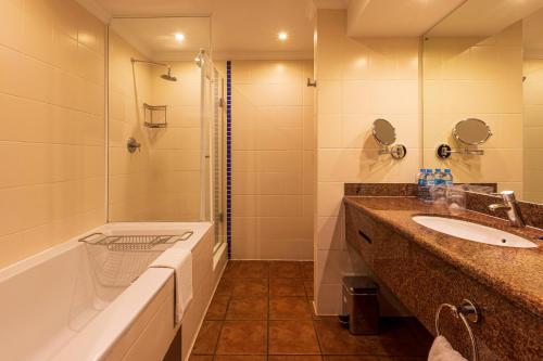 a bathroom with a tub and a sink and a shower at Hotel Cardoso in Maputo