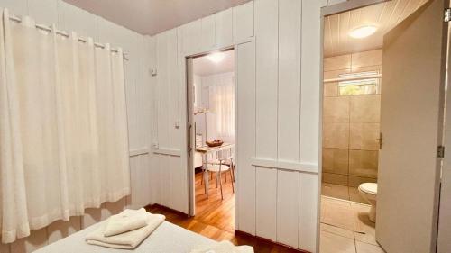 a white bathroom with a toilet and a shower at Casa Próximo ao Centro e Hospital in Blumenau