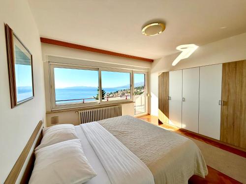 a bedroom with a large bed and a large window at Blue View Apartment in Opatija