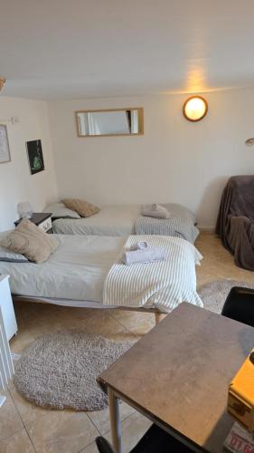 two beds in a white room with a table at Studio atypique avec Piscine à partager en option in La Ferté-Gaucher