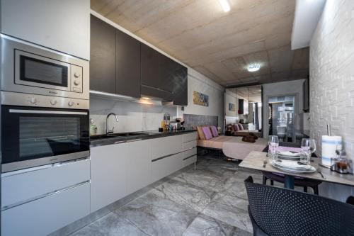 a kitchen with white cabinets and a living room at Seafront, lovely modern studio. in St. Julianʼs