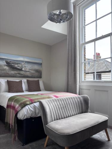 a bedroom with a bed and a chair and a window at Fleur De Lis Hotel in Sandwich