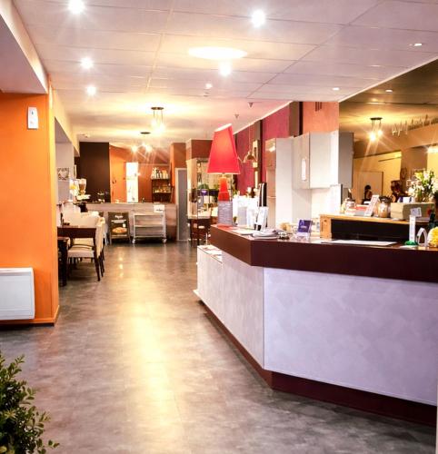 a restaurant with a counter and a dining area at The Originals City, Hôtel Mâcon Sud in Chaintré