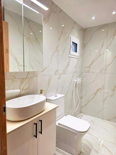 a white bathroom with a sink and a toilet at Anthouli Homes 2, steps from beach and centre in Kardamaina
